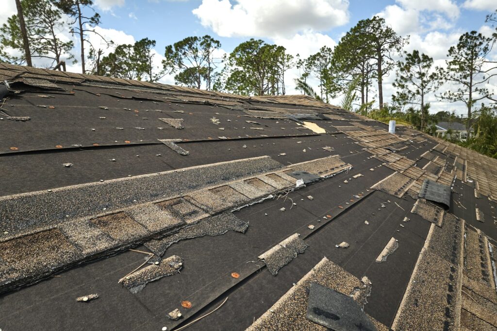 Damaged house roof with missing shingles after hurricane Ian in Florida.